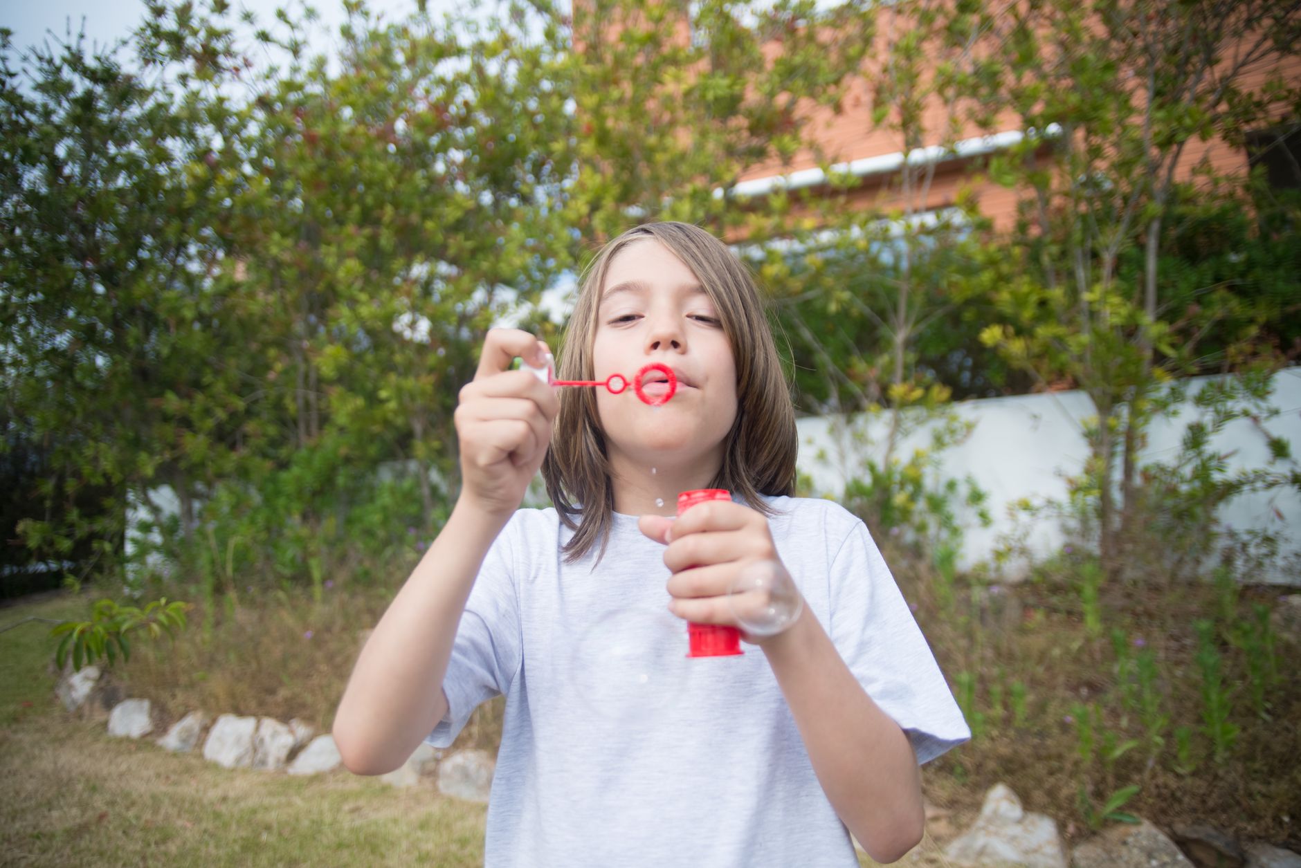 Enfant qui ouvre un tube de bulles de savon personnalisé dans un jardin