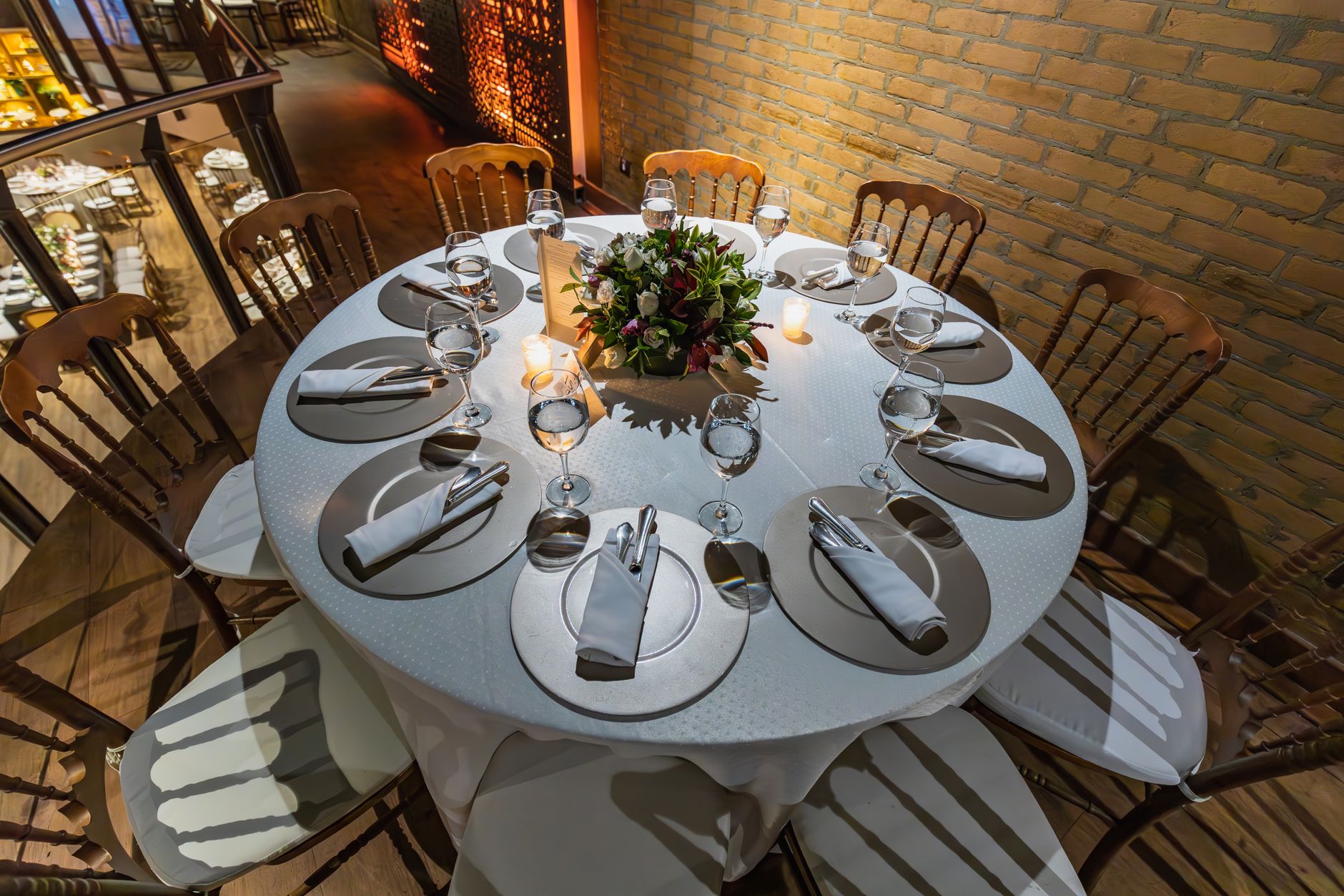 Table ronde dressée avec couverts et centre de table fleuri