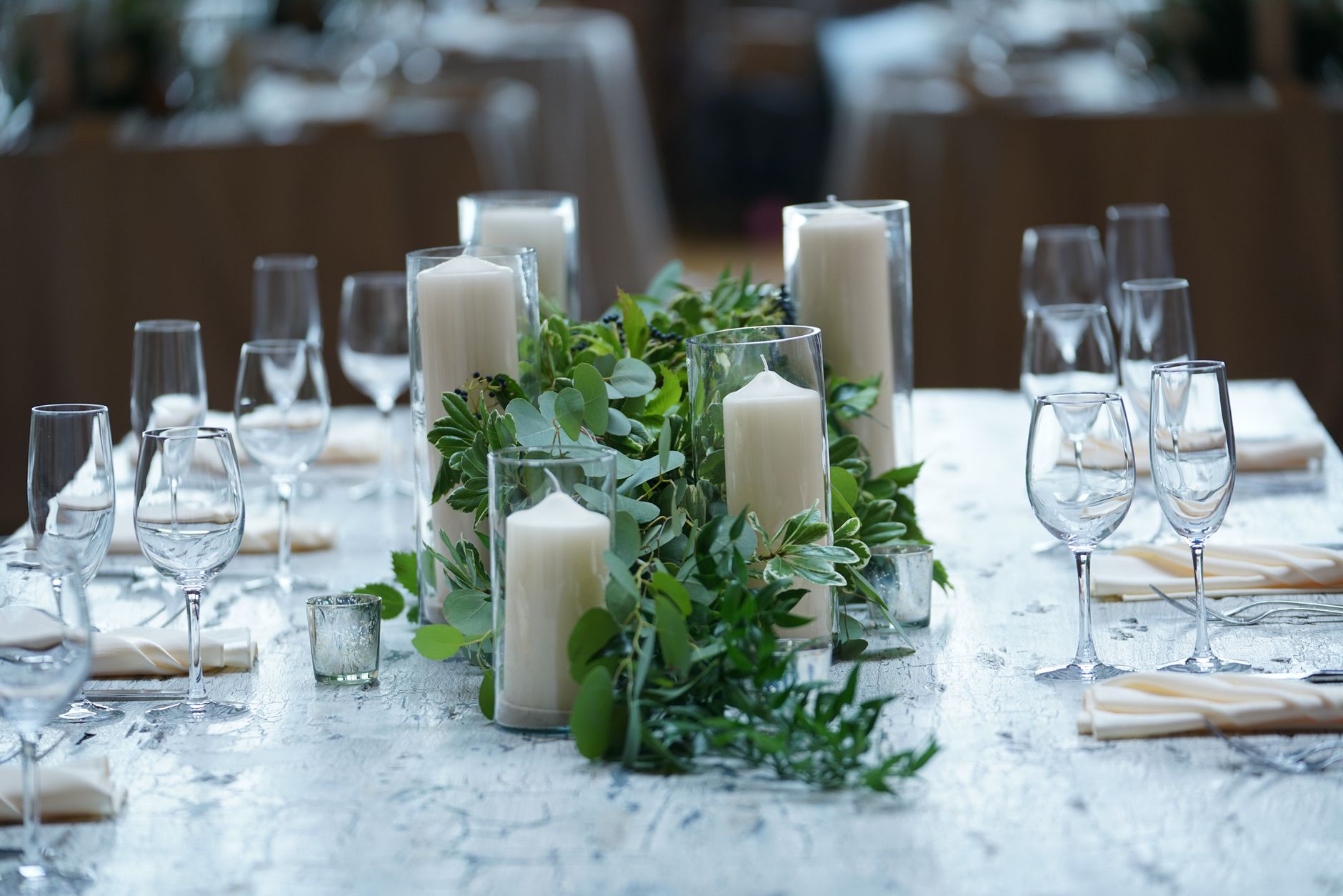 Bougies blanches et feuillage sur une table de réception