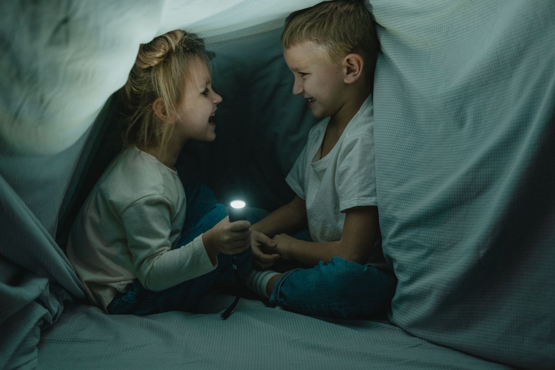 Deux enfants rient dans une cabane en couvertures