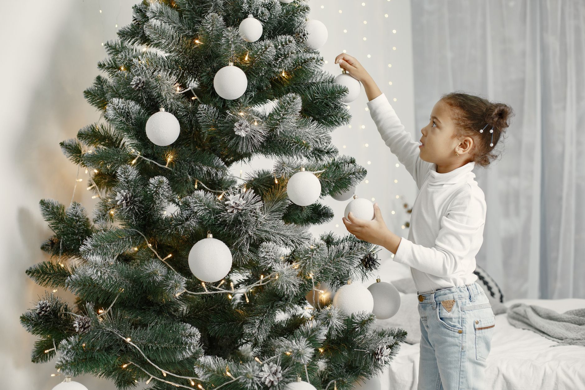 Une enfant accroche une décoration sur un sapin de Noël