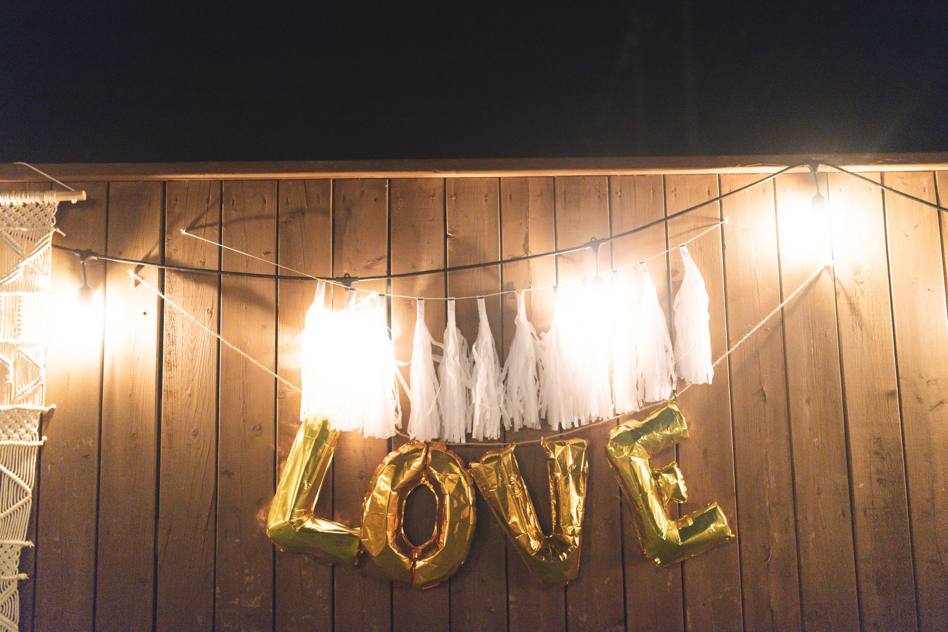 Ballons dorés et guirlande LED sur un mur en bois