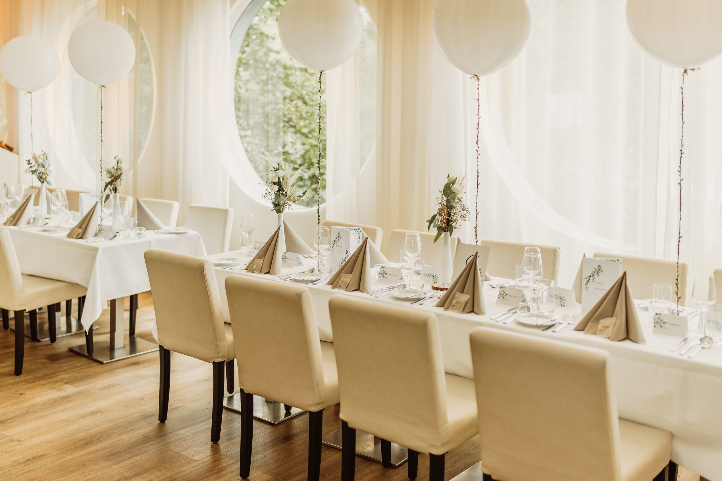 Salle de fête aux ballons blancs et tables dressées
